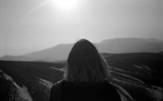 Person gazing at a mountainous landscape.