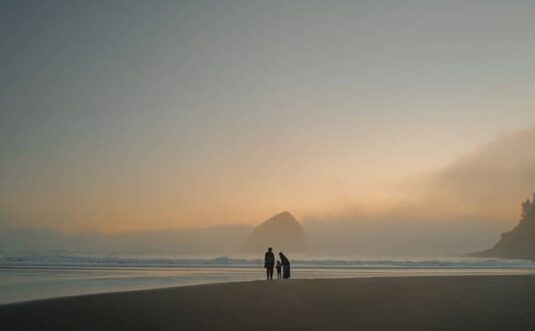 Family walking on a foggy beach at sunset