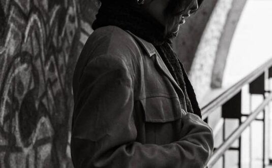 Woman in coat stands near graffiti wall